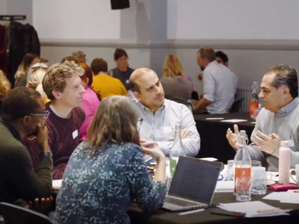 Informal meeting around tables, with laptops, drinks and snacks